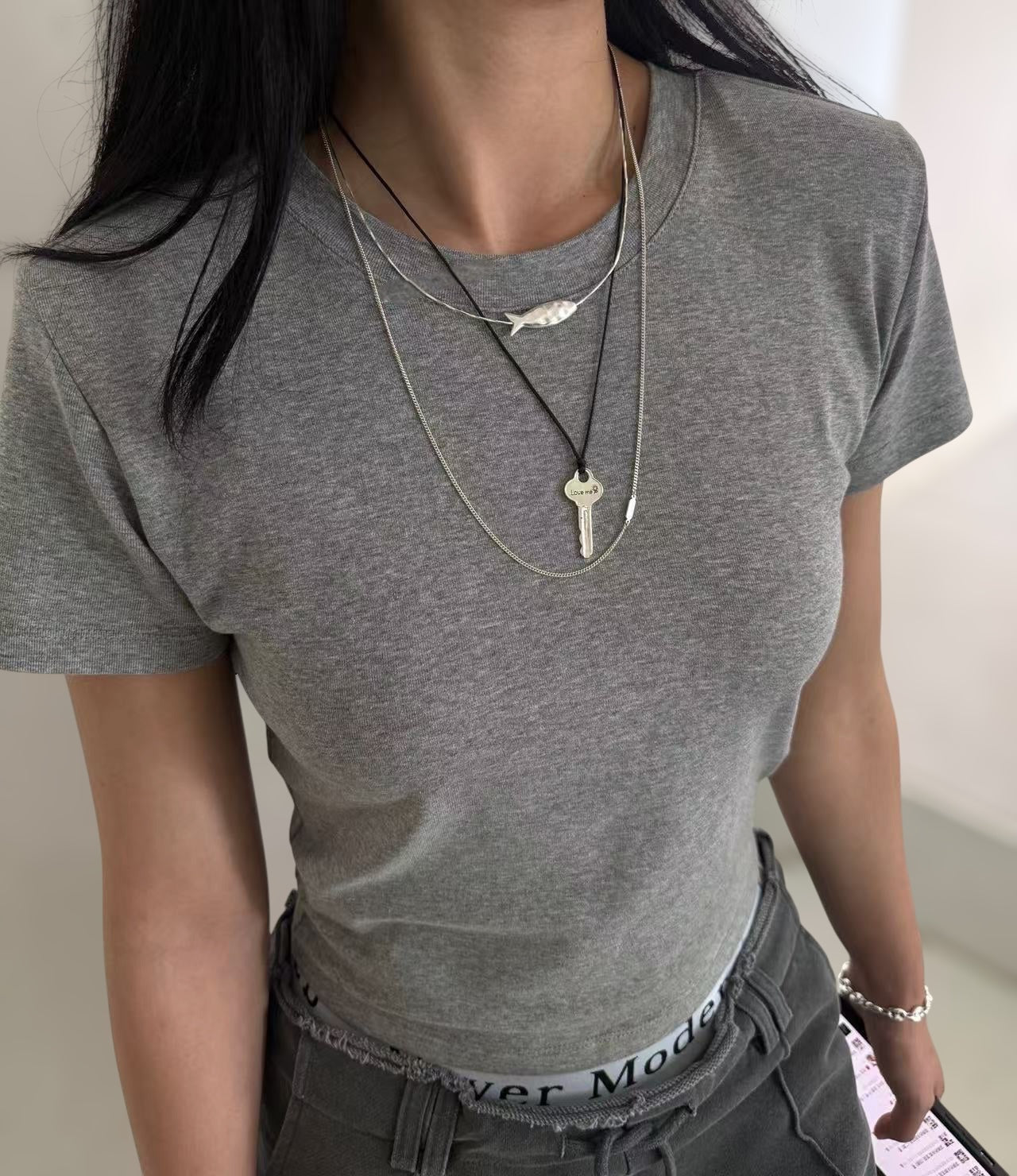 小丞飾銀色小魚造型鎖骨鍊，搭配細緻蛇骨鍊與鑰匙吊墜，展現簡約優雅的層次感穿搭