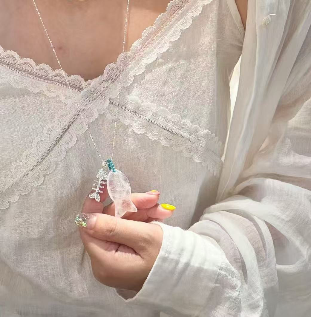 小丞飾魚骨造型長項鍊，結合半透明晶石魚身與金屬魚骨吊墜，點綴亮藍色珠飾，展現海洋風格的精緻飾品。